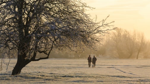 Couple walking at Flatford in frosty winter landscape